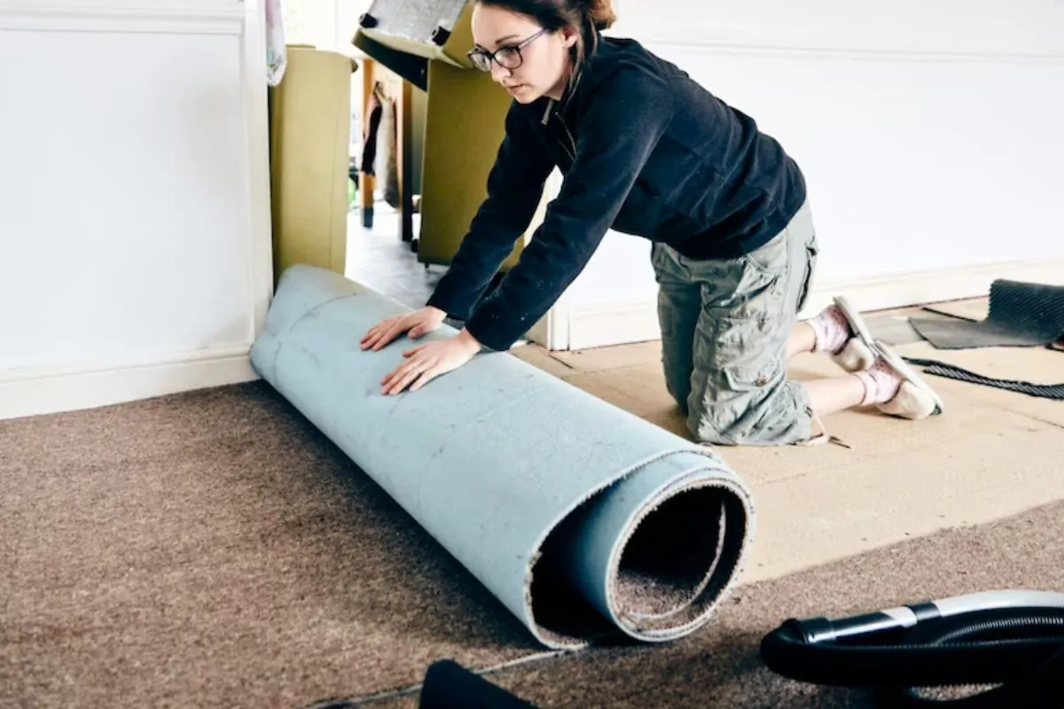 woman rolling the old carpet for disposal