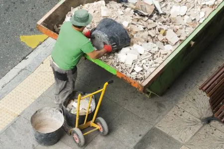 professional contractor throwing concrete debris on a dumpster