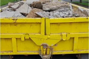 yellow dumpster with concrete