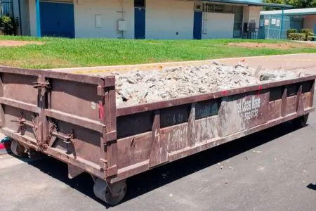 brown dumpster full of concrete debris